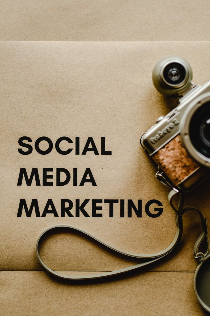 Vue rapprochée d’un appareil photo ancien à côté d’un texte sur le marketing des réseaux sociaux, sur fond brun.